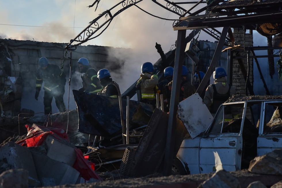 Members of the Ukrainian State Emergency Service clear the rubble at the building which was...