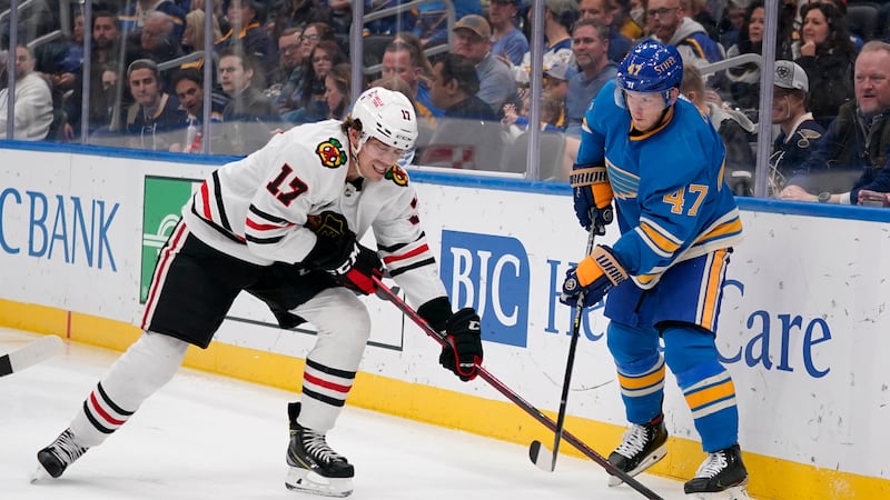 St. Louis Blues' Torey Krug (47) passes around Chicago Blackhawks' Dylan Strome (17) during...