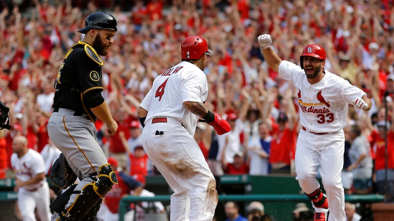 St. Louis Cardinals' Yadier Molina, center, celebrates with teammate Daniel Descalso, right,...