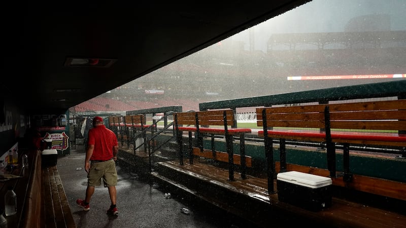 A member of the Busch Stadium grounds crew walks through the St. Louis Cardinals dugout at the...