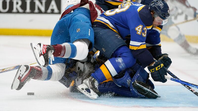 Colorado Avalanche's Nazem Kadri, left, falls on St. Louis Blues goaltender Jordan Binnington...