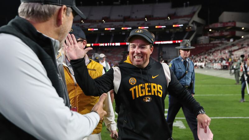 Missouri head coach Eliah Drinkwitz celebrates with a fan after winning an NCAA college...