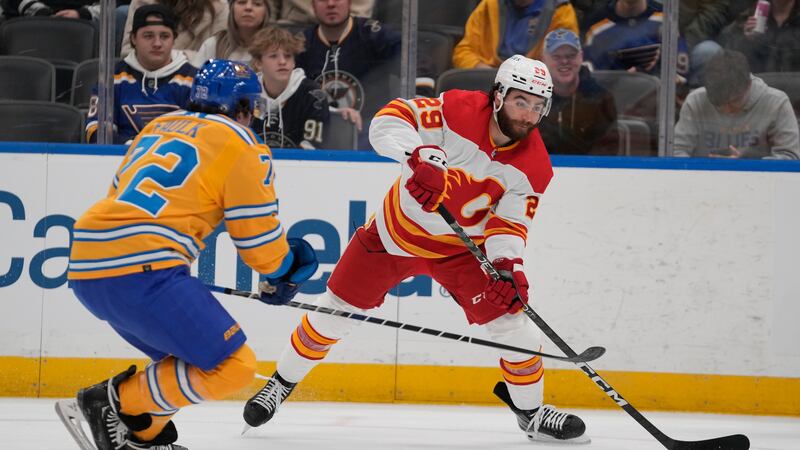 Calgary Flames' Dillon Dube (29) passes around St. Louis Blues' Justin Faulk (72) during the...