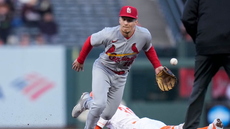 St. Louis Cardinals shortstop Tommy Edman is unable to catch a throw from catcher Willson...